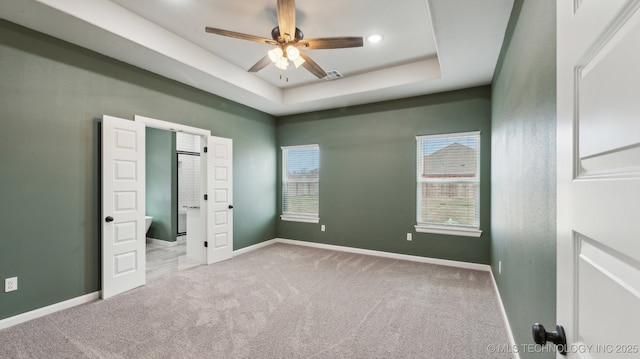 unfurnished bedroom with a tray ceiling, carpet floors, and baseboards