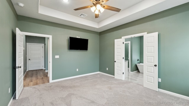 unfurnished bedroom with a raised ceiling, carpet flooring, and visible vents