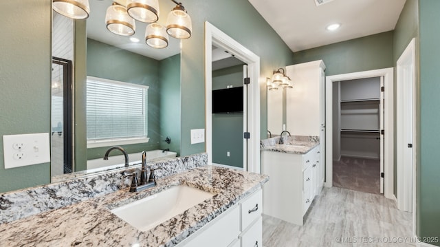 full bathroom with a sink, two vanities, and a spacious closet