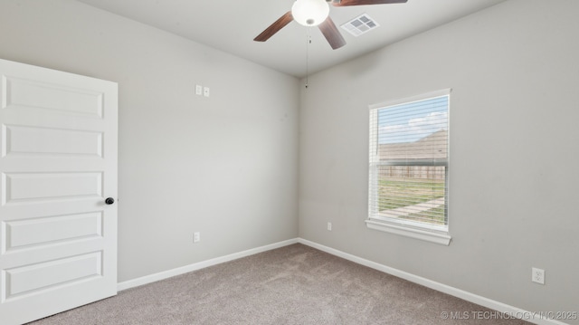 empty room with carpet flooring, a ceiling fan, visible vents, and baseboards