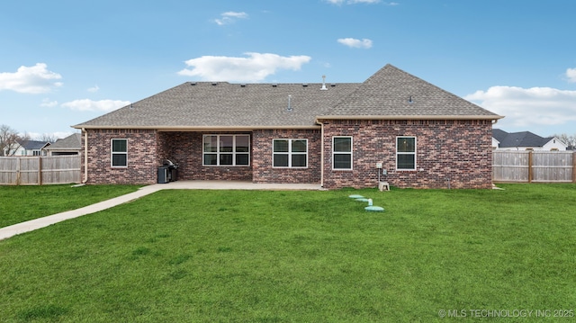 rear view of property with a yard, a shingled roof, and a fenced backyard