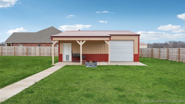 exterior space with a lawn, a garage, a fenced backyard, an outdoor structure, and metal roof