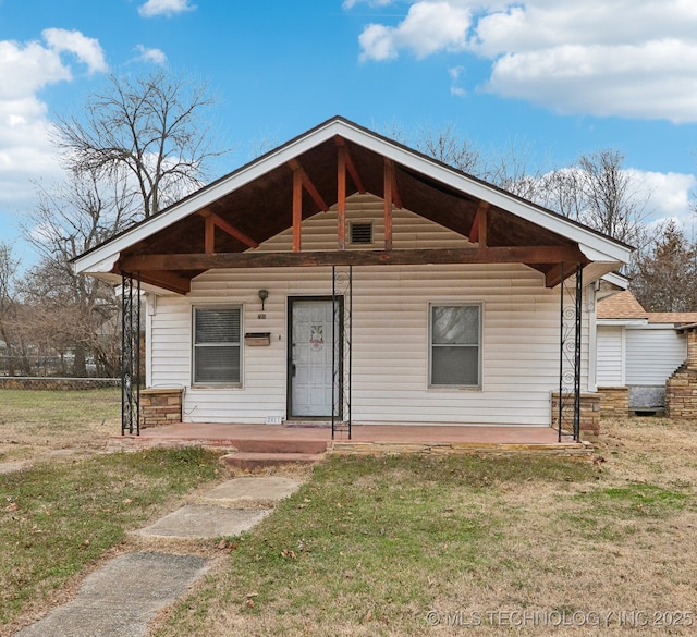 bungalow-style house featuring covered porch, a front lawn, and fence