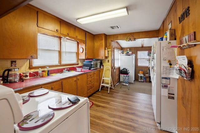 kitchen with visible vents, stainless steel microwave, light wood-style floors, brown cabinetry, and a sink