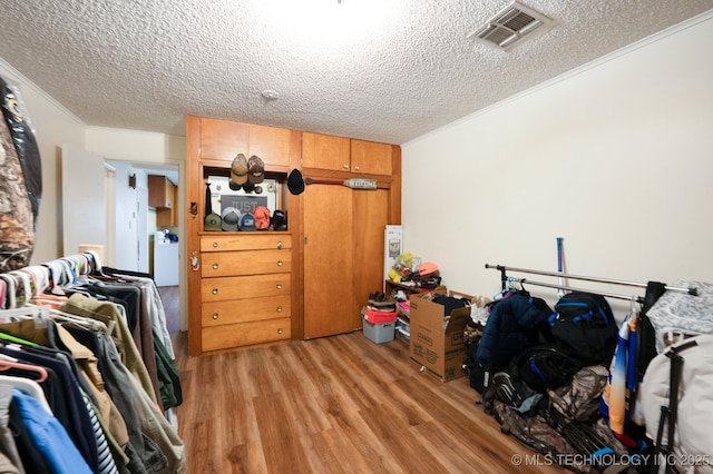 interior space with light wood finished floors, visible vents, crown molding, washer / clothes dryer, and a textured ceiling