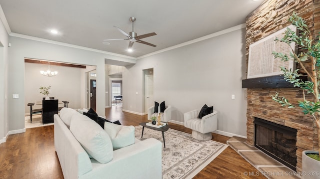 living area with dark wood-style flooring, a stone fireplace, a ceiling fan, baseboards, and ornamental molding