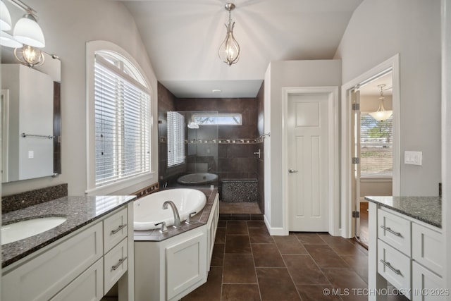 bathroom featuring a garden tub, a walk in shower, tile patterned floors, two vanities, and baseboards