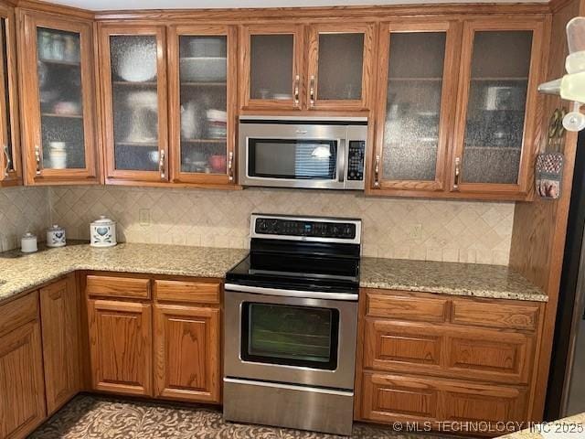 kitchen with light stone counters, brown cabinets, and appliances with stainless steel finishes