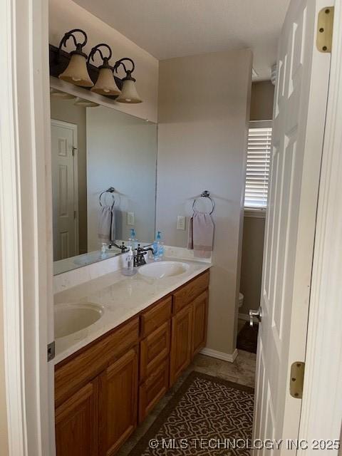 bathroom with double vanity, toilet, and a sink