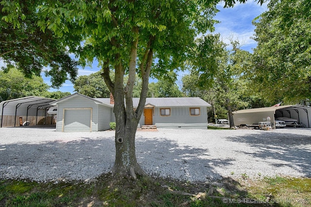 view of front of house with crawl space, a detached carport, driveway, and metal roof