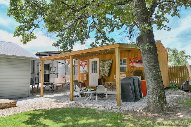 back of house featuring metal roof, an outbuilding, and fence