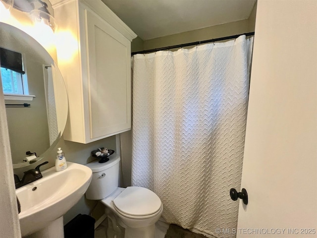 bathroom featuring toilet, a shower with shower curtain, and a sink