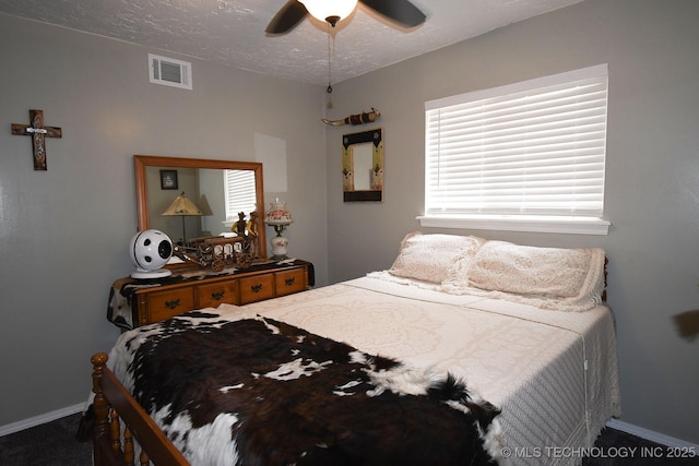 bedroom with visible vents, baseboards, a textured ceiling, and a ceiling fan