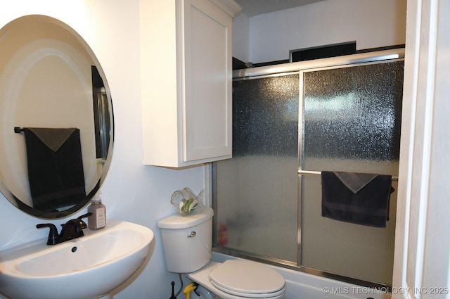 full bath featuring combined bath / shower with glass door, toilet, and a sink