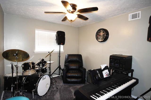 playroom with visible vents, a textured ceiling, carpet flooring, and a ceiling fan