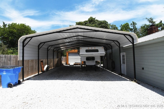 view of parking with a detached carport and fence