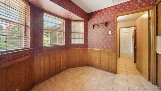 empty room featuring wallpapered walls, wood walls, and wainscoting