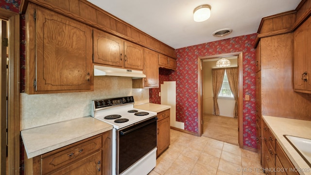 kitchen with under cabinet range hood, white electric stove, brown cabinetry, wallpapered walls, and light countertops