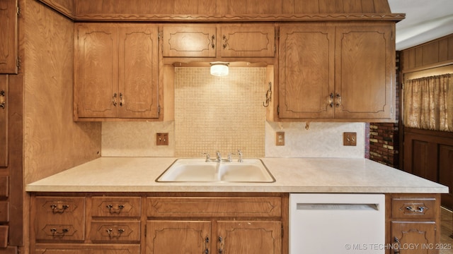 kitchen featuring a sink, tasteful backsplash, white dishwasher, and light countertops