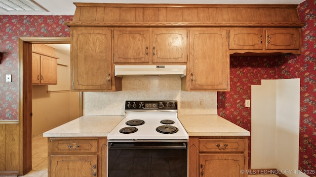 kitchen featuring under cabinet range hood, electric stove, light countertops, and wallpapered walls