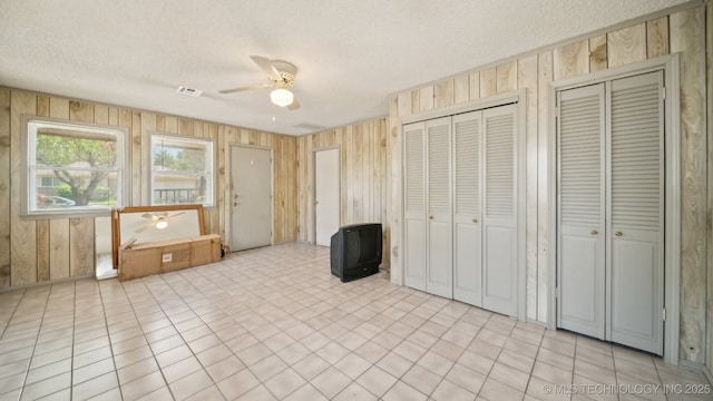 spare room with visible vents, a textured ceiling, and wood walls