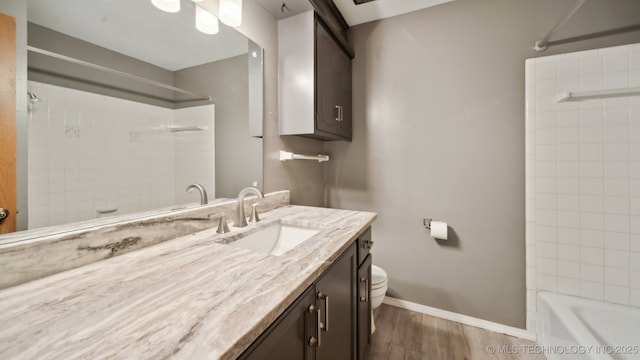 bathroom featuring baseboards, toilet, shower / tub combination, wood finished floors, and vanity