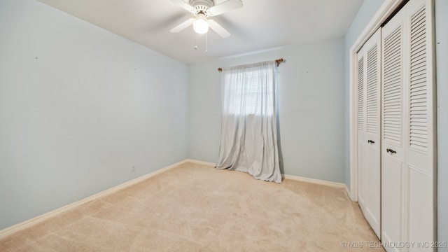 unfurnished bedroom featuring a closet, baseboards, light colored carpet, and a ceiling fan