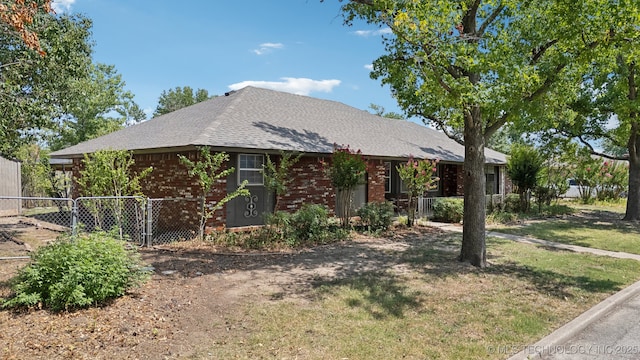 single story home with a front lawn, a gate, fence, a shingled roof, and brick siding