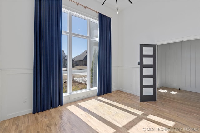 spare room with wood finished floors and wainscoting