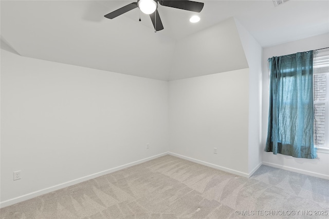 empty room with carpet flooring, a ceiling fan, baseboards, and vaulted ceiling