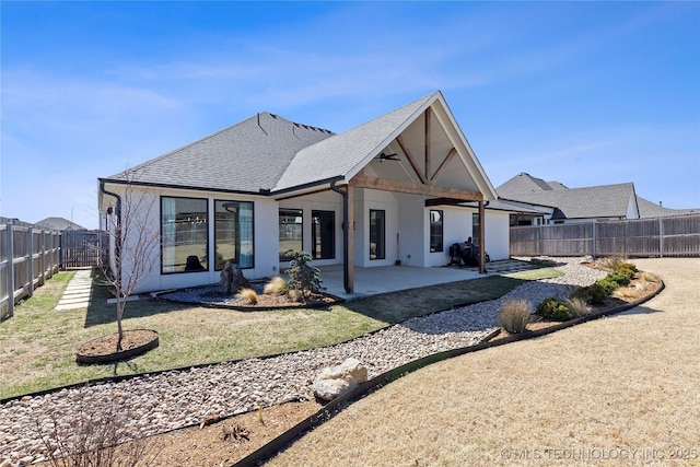 back of house with roof with shingles, stucco siding, a yard, a fenced backyard, and a patio