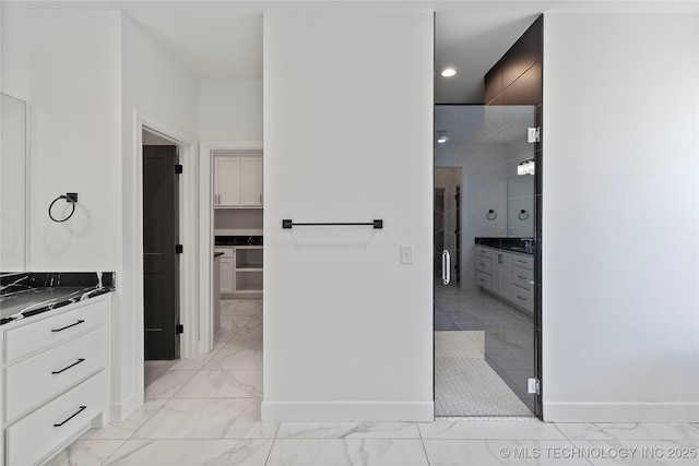 bathroom with baseboards, marble finish floor, a shower stall, and vanity