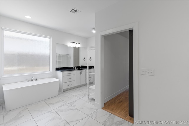 bathroom with a freestanding tub, visible vents, marble finish floor, baseboards, and vanity