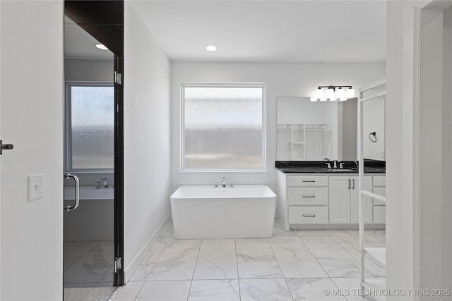 bathroom featuring marble finish floor, recessed lighting, baseboards, a freestanding bath, and vanity