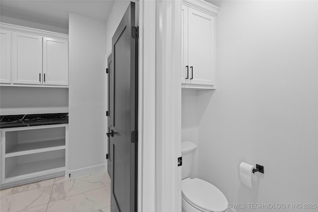 bathroom with baseboards, toilet, and marble finish floor