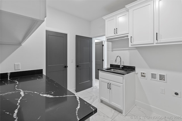 interior space with dark stone countertops, baseboards, a sink, white cabinetry, and marble finish floor