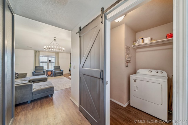 washroom featuring a barn door, baseboards, washer / dryer, and wood finished floors