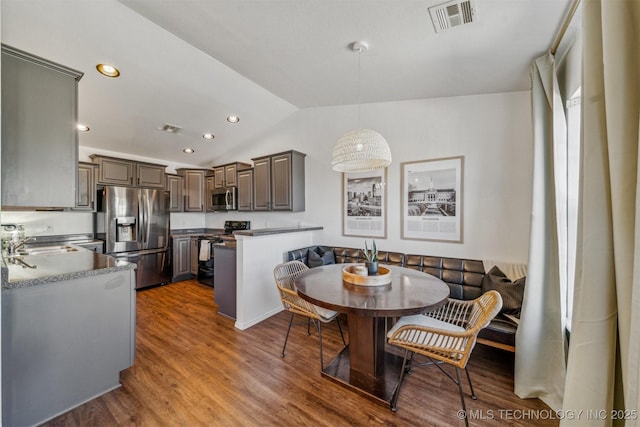 dining space with lofted ceiling, wood finished floors, visible vents, and breakfast area