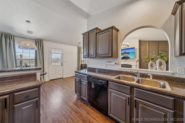 kitchen with a sink, dark countertops, dark wood finished floors, dishwasher, and hanging light fixtures