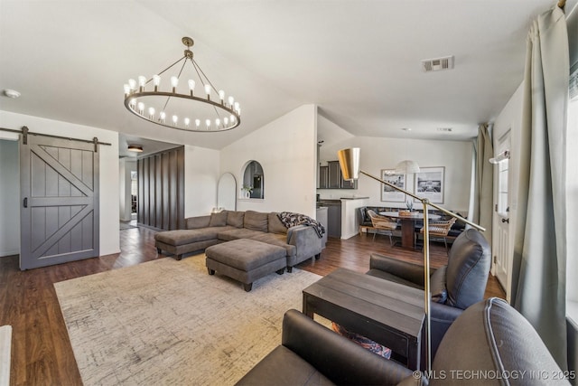 living room with dark wood finished floors, visible vents, lofted ceiling, and a barn door