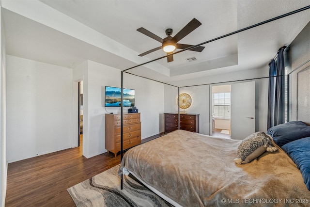 bedroom with visible vents, baseboards, ceiling fan, wood finished floors, and a raised ceiling