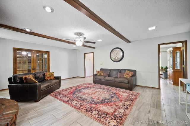 living area with beam ceiling, a textured ceiling, french doors, light wood finished floors, and ceiling fan