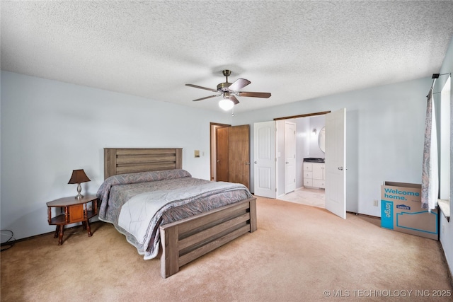 bedroom with light carpet, a ceiling fan, a textured ceiling, ensuite bath, and baseboards