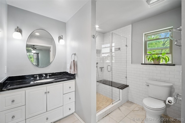 bathroom with toilet, marble finish floor, a stall shower, tile walls, and vanity