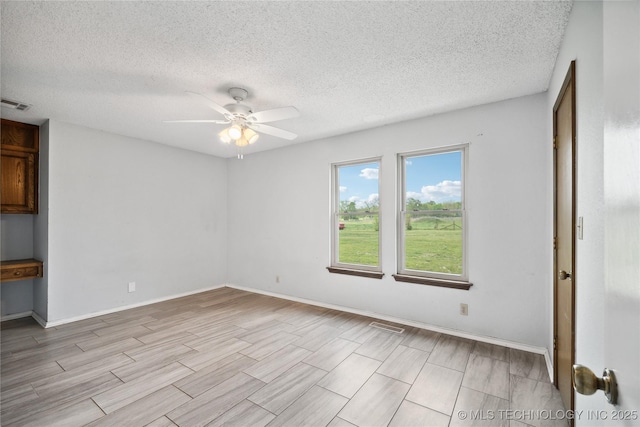 spare room with visible vents, baseboards, ceiling fan, and wood tiled floor