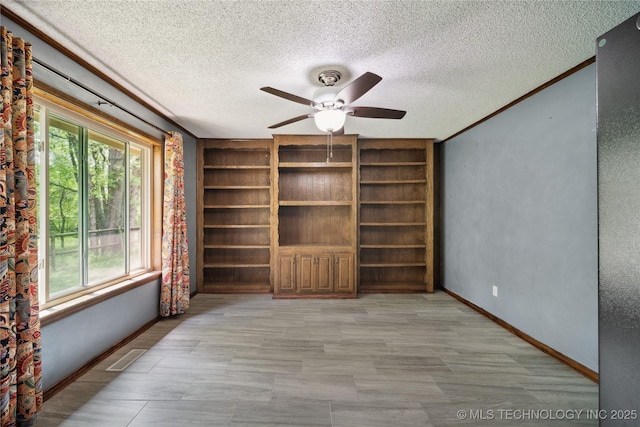 unfurnished room featuring visible vents, baseboards, a textured ceiling, and ornamental molding