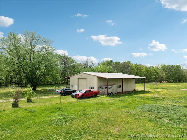 view of yard with a detached garage, an outbuilding, and driveway