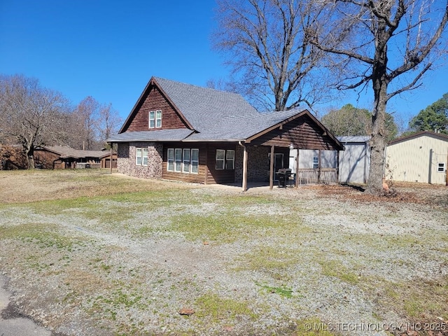 view of front of home featuring an outbuilding, a front lawn, and roof with shingles