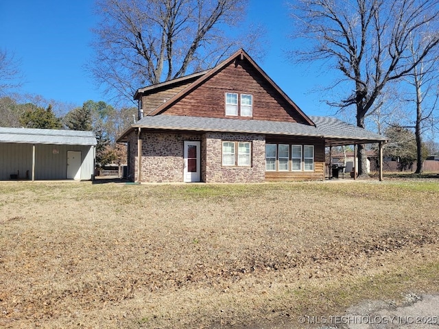 back of house with an outdoor structure, a lawn, and an outbuilding