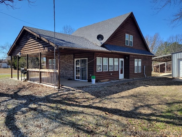 back of property featuring a carport, faux log siding, and a shingled roof